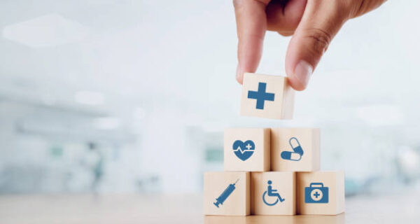 Close up man hand arranging wood block with healthcare medical icon on hospital background. Health care and Health insurance concept.