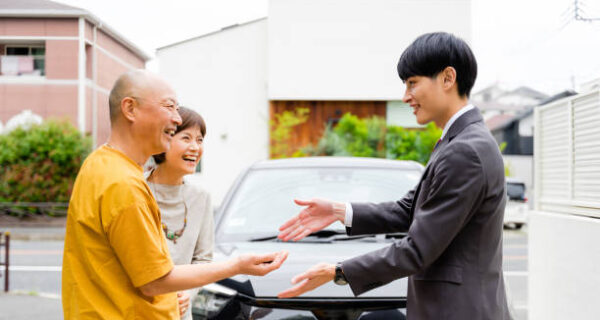 An elderly couple who buy a car and give the key from a dealer's man