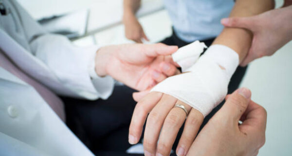 The doctor wraps a bandage on the arm of the injured patient.